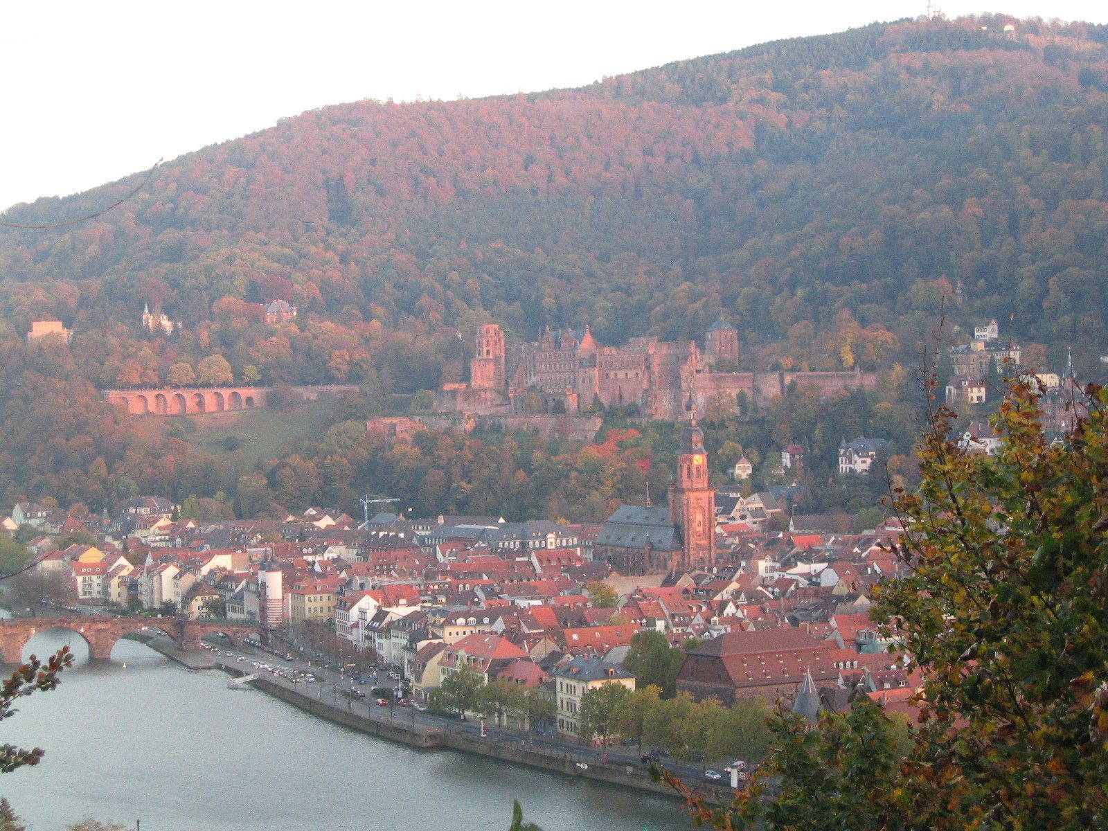 A historic town with a river, red-roofed buildings, and a prominent church tower.