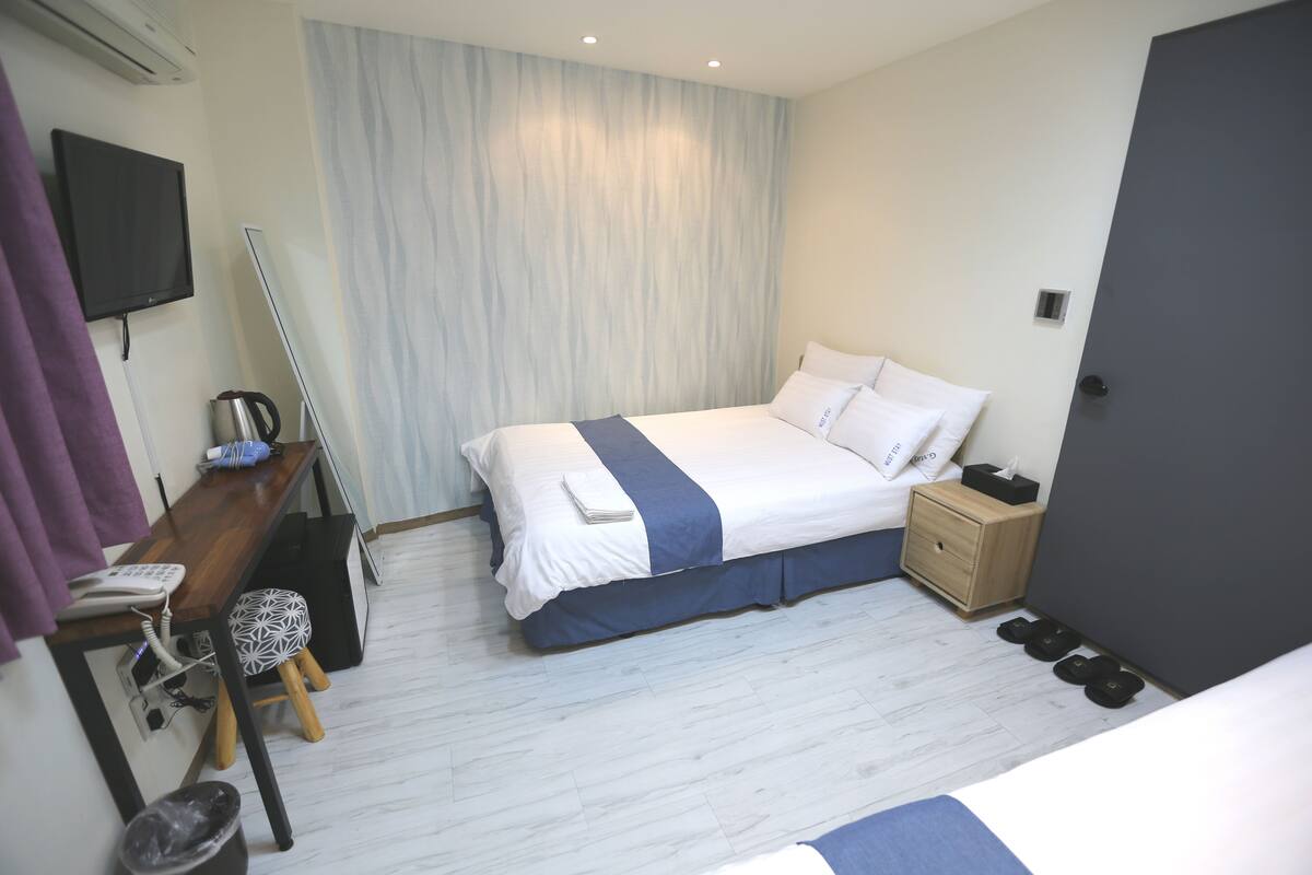 A modern hotel room with a bed, bedside table, and a TV mounted on the wall.