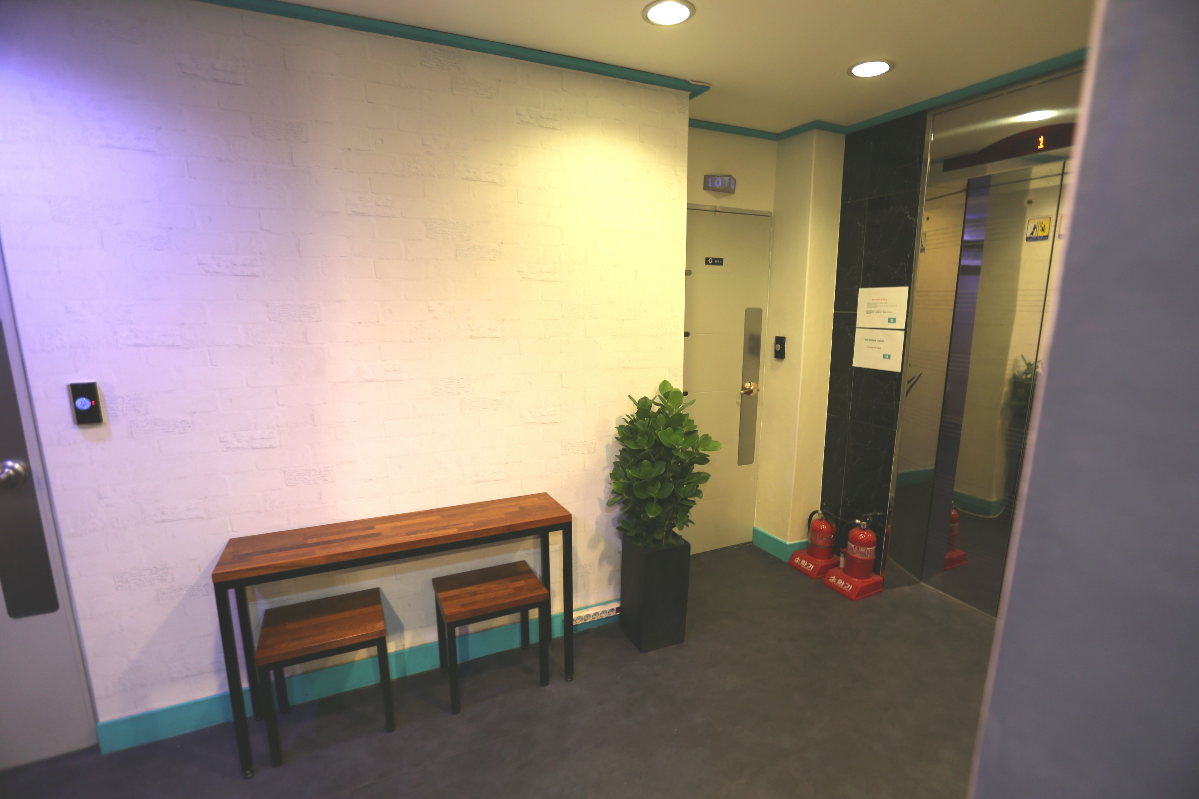 A hallway with a wooden bench, a potted plant, and a fire extinguisher.