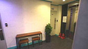 A hallway with a wooden bench, a potted plant, and a fire extinguisher.