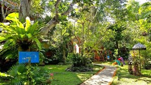 A garden pathway with lush greenery and a small playground area. - Puri Cendana Resort Bali (Seminyak)