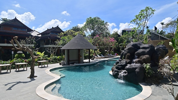 A swimming pool with a rock feature, surrounded by a tiled deck and a small pavilion. - Puri Cendana Resort Bali (Seminyak)