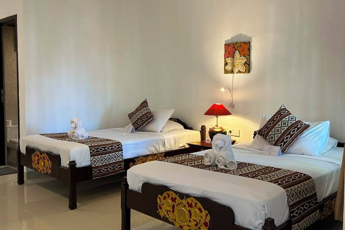 A hotel room with two beds, a red lamp, and a wall-mounted air conditioner.