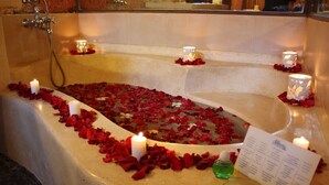 A bathtub filled with rose petals and candles, with a menu on the side. - Puri Cendana Resort Bali (Seminyak)