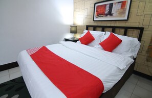 A neatly made bed with white and red bedding, a bedside table with a lamp, and a framed picture on the wall.
