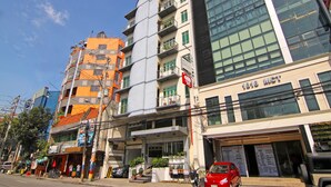 Um edifício de vários andares com fachada moderna em vidro, entrada visível e uma placa indicando o ano de 1818.