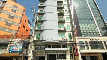 A multi-story building with balconies, a car parked in front, and a sign indicating '1818 LMT'.