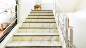 A staircase with metal railings and a vase with flowers at the top. - Newgrange Condotel (Quezon City)