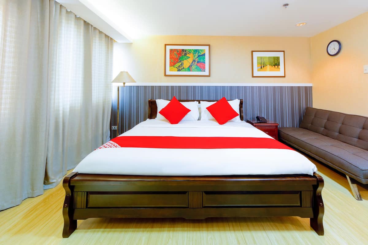 A hotel room with a large bed, a sofa, and two framed pictures on the wall.