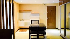 A modern kitchen with a dining area, a wooden door, and a sliding glass door. - Newgrange Condotel (Quezon City)