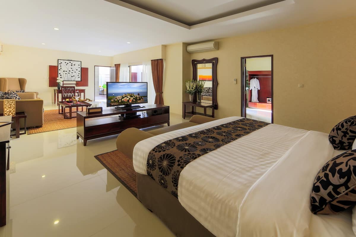 Een moderne hotelkamer met een groot bed, een televisie, een bureau en een zithoek.