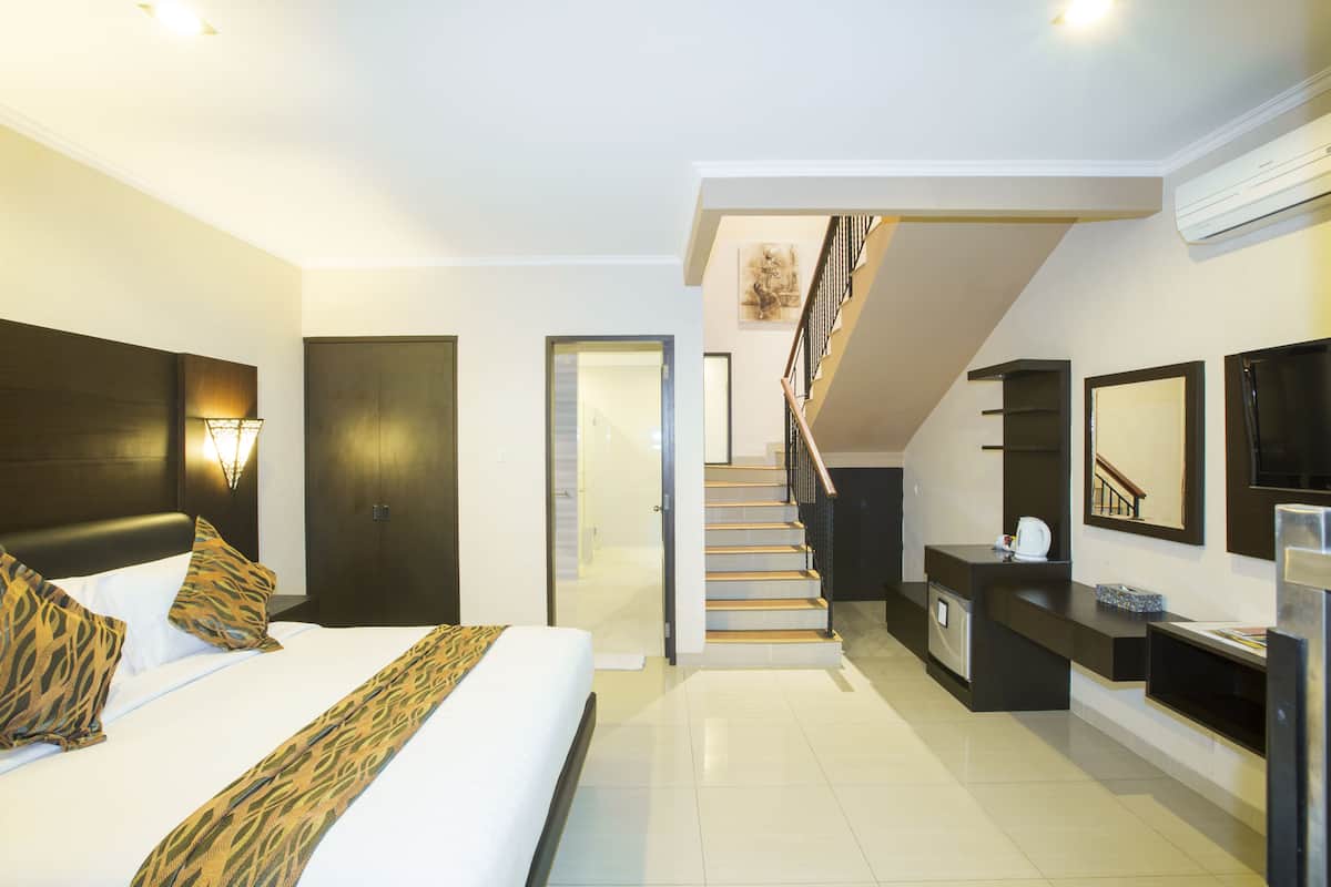 Een moderne hotelkamer met een groot bed, een bureau en een trap naar een verdieping boven.