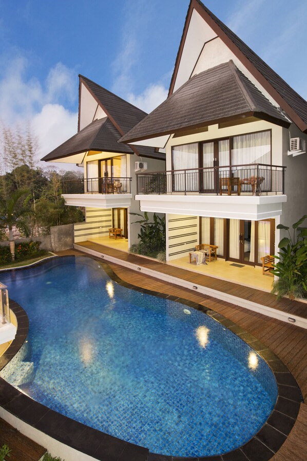 Una piscina al aire libre, sombrillas, sillones reclinables de piscina