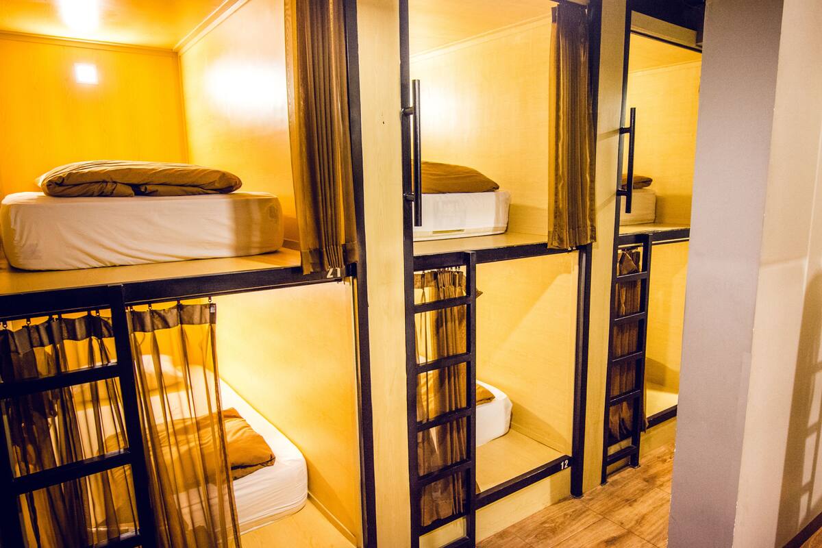 A dormitory-style room with bunk beds and curtains.