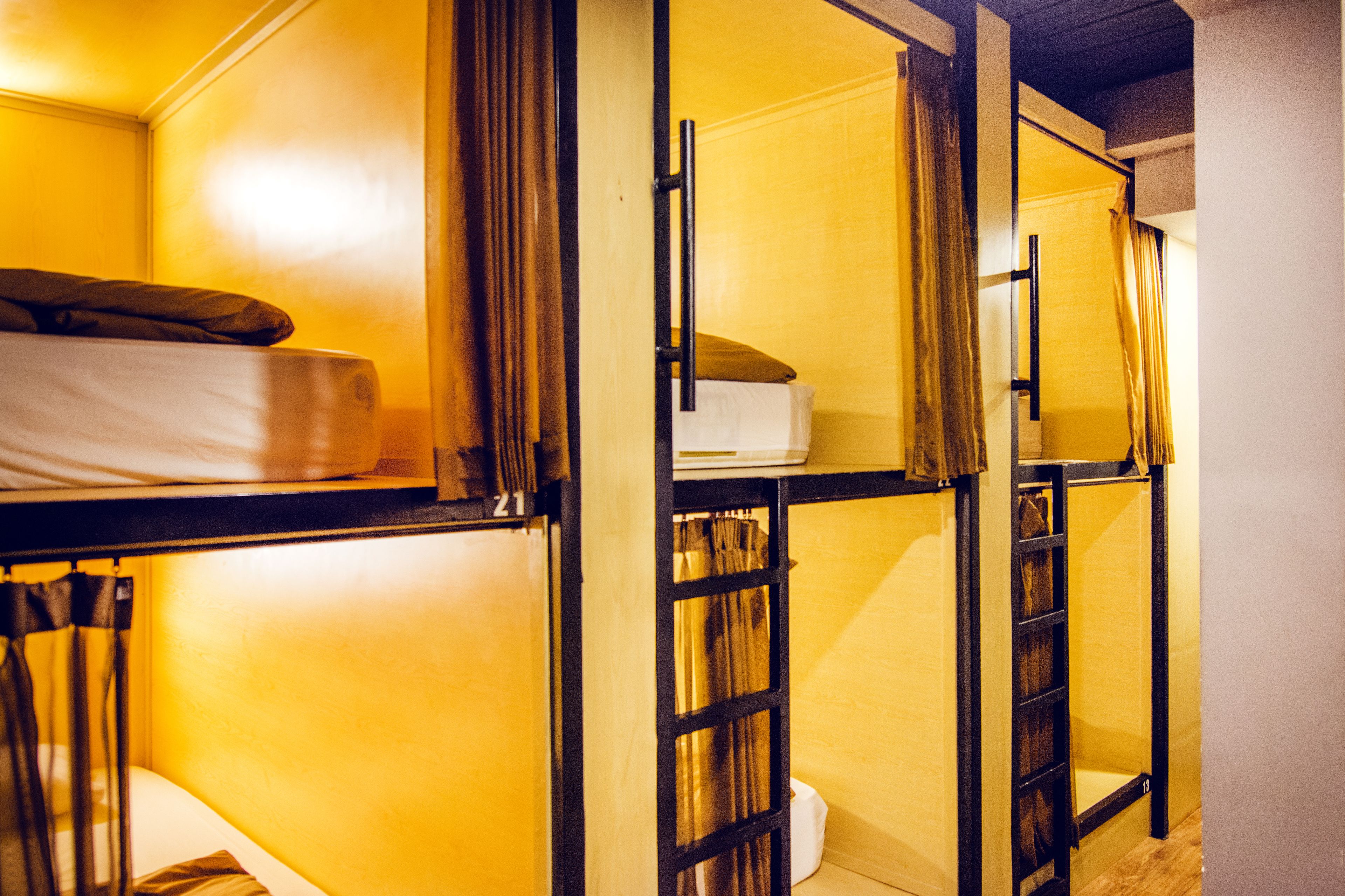 A dormitory-style room with bunk beds, a small table, and a curtain.