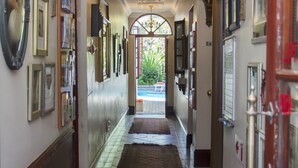 A hallway with a chandelier, framed pictures, and a rug leading to an outdoor area. - Brighton Lodge (Gqeberha (Port Elizabeth))
