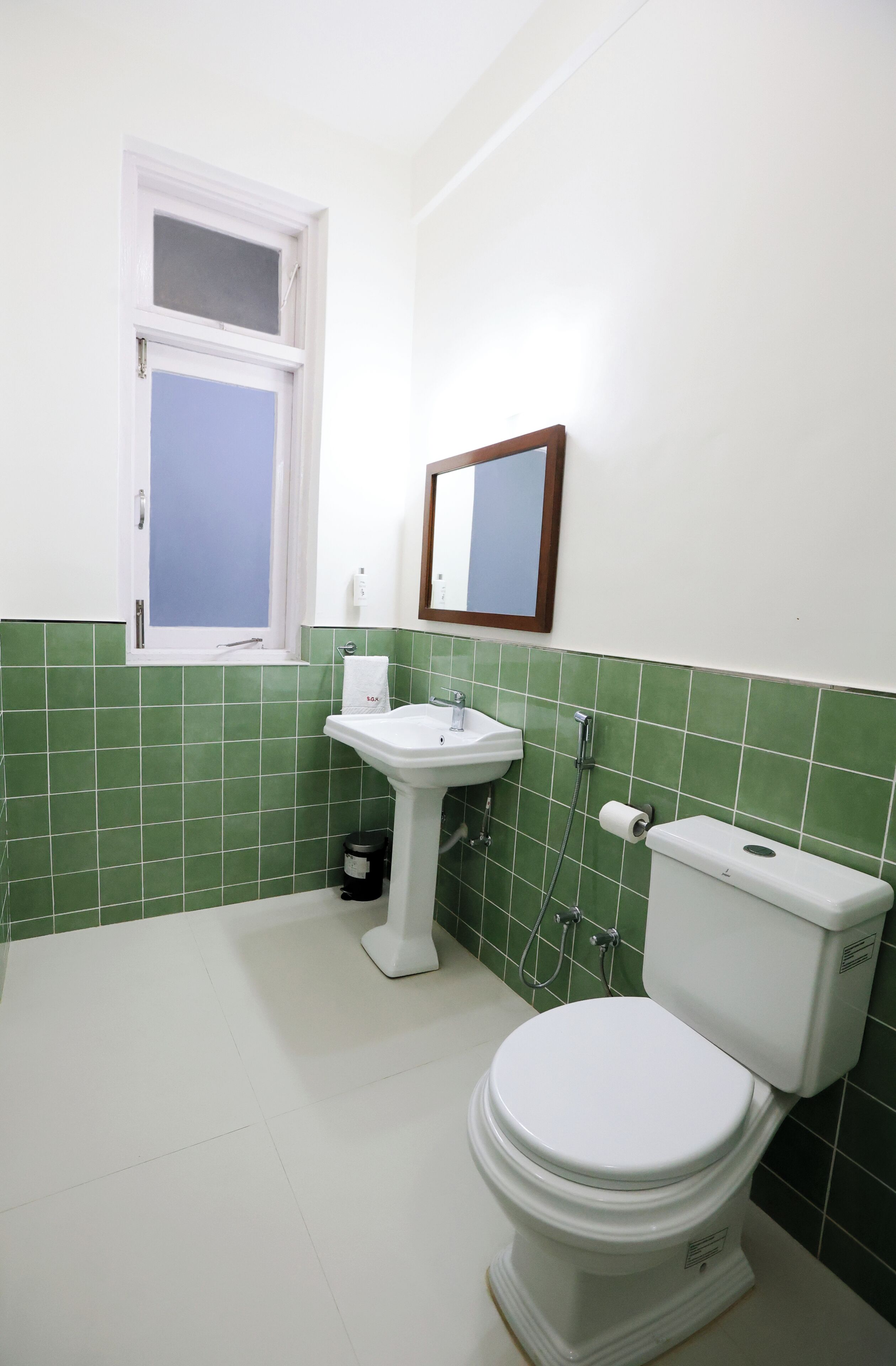 A bathroom with a toilet, sink, and window.