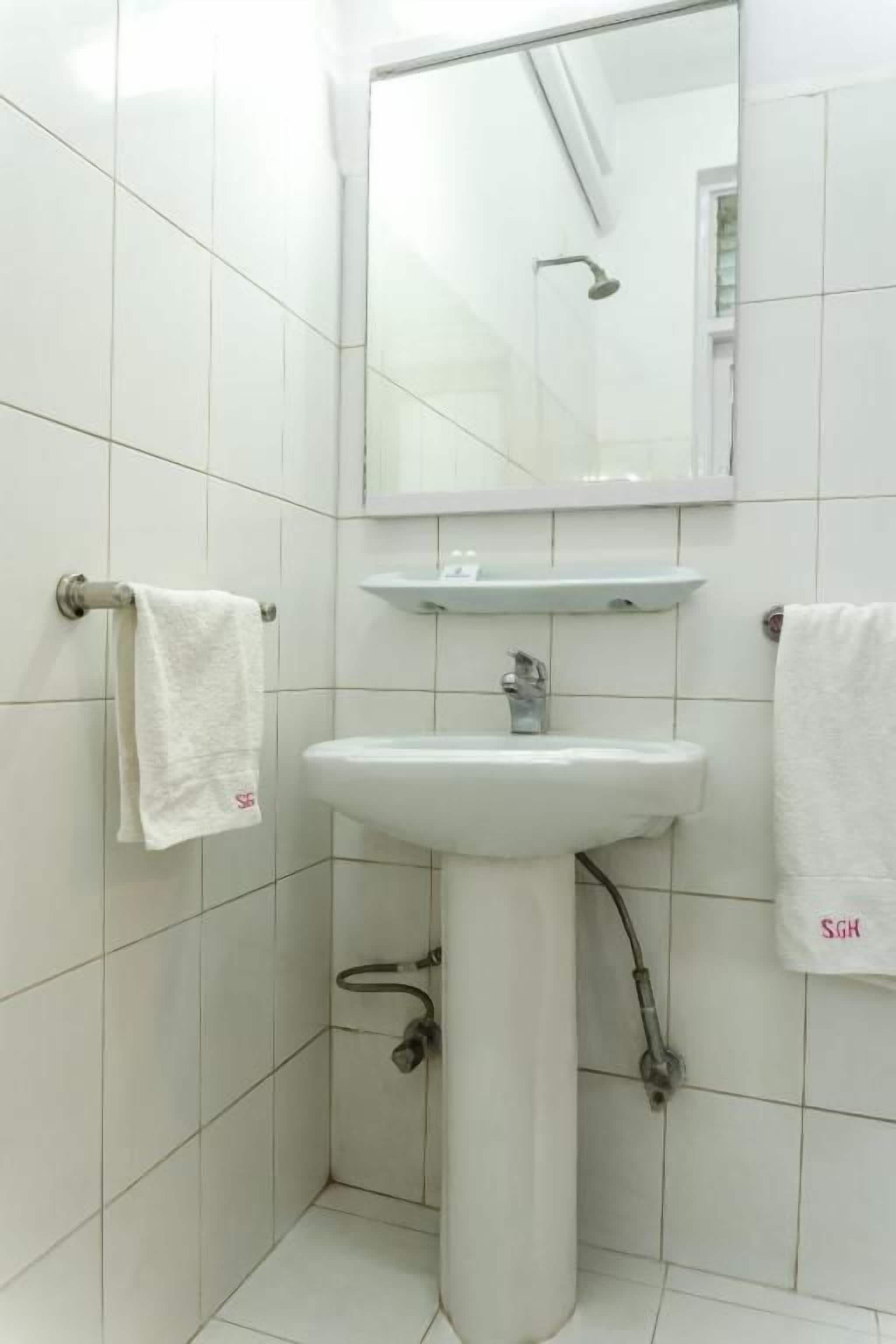 Un baño con lavamanos blanco, espejo y barra para toallas.