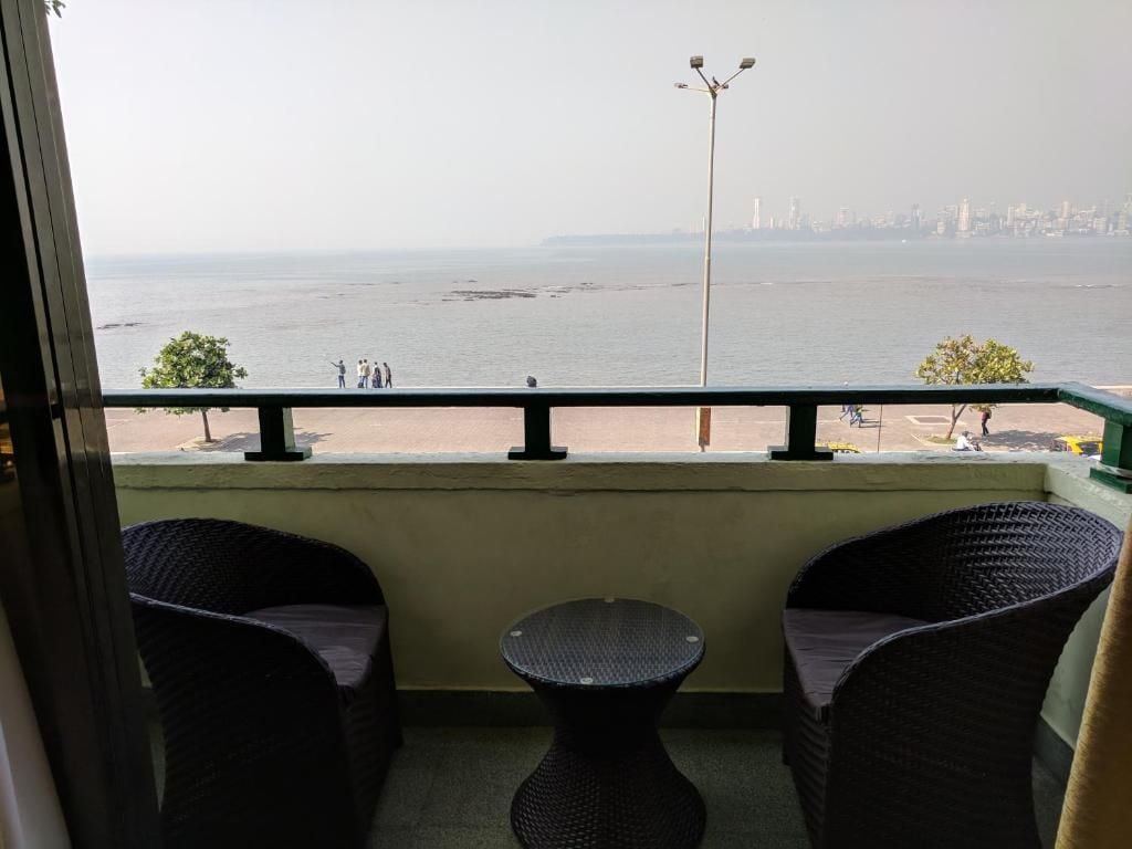 Een balkon met rieten meubilair en uitzicht op zee en de stadshemel.