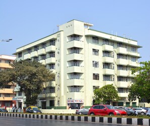 A multi-story building with a flat facade, several balconies, and a ground-level commercial space with signage. - Sea Green Hotel (Mumbai)