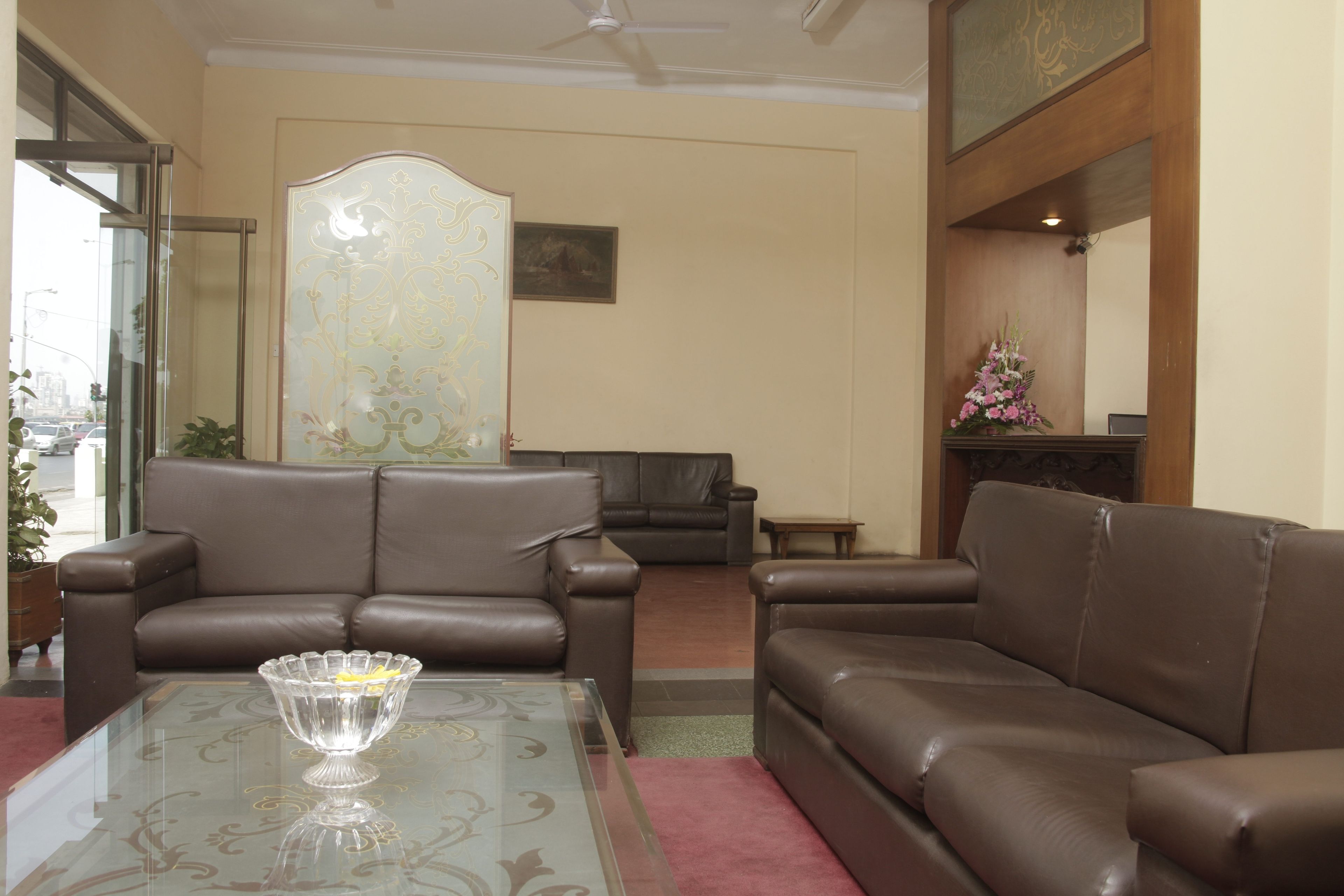 A living room with two brown leather sofas, a glass coffee table with a decorative bowl, and a large mirror on the wall.