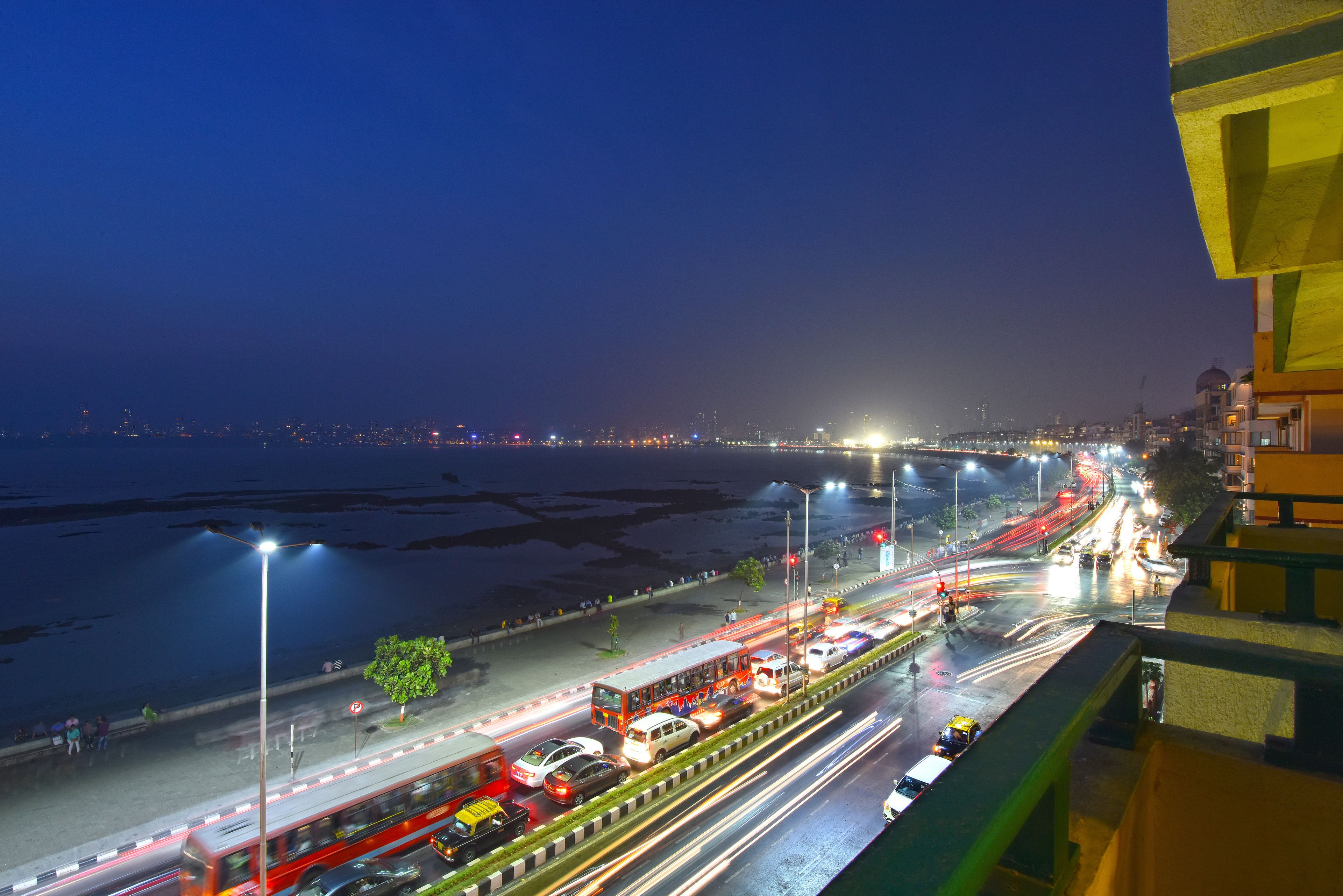 A nighttime cityscape with a busy highway, streetlights, and a body of water.