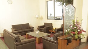 Ein Wohnzimmer mit braunen Sofas, einem Glastisch und einem Holztisch mit Blumen in einer Vase.