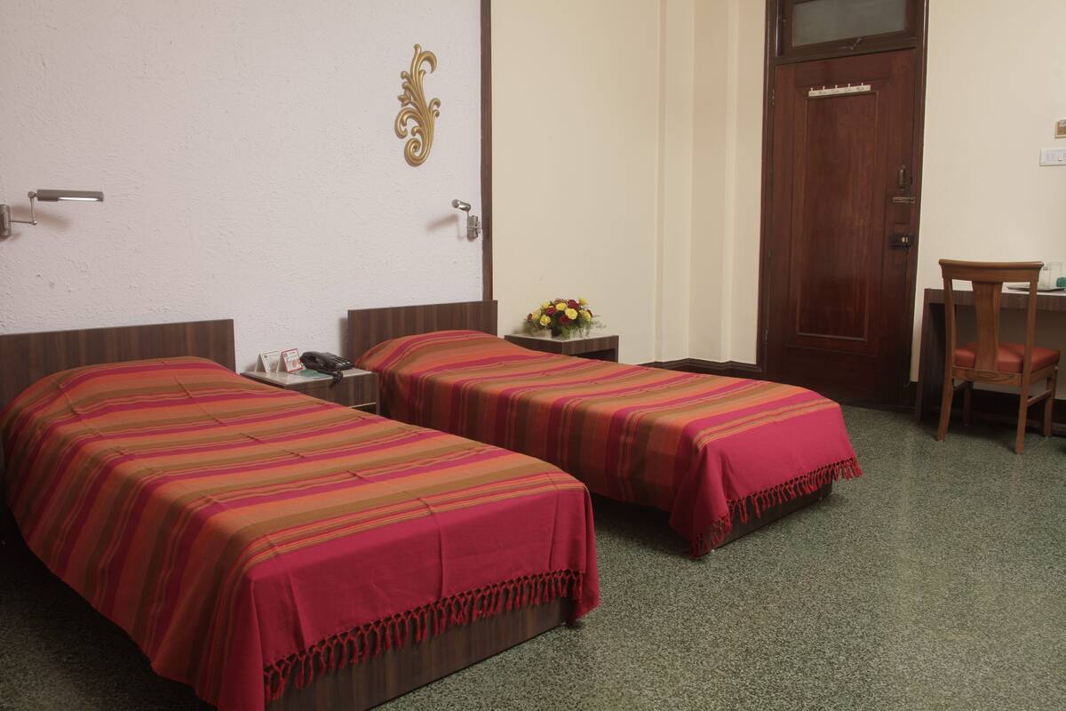 Habitación de hotel con dos camas, un escritorio, una silla y una puerta.