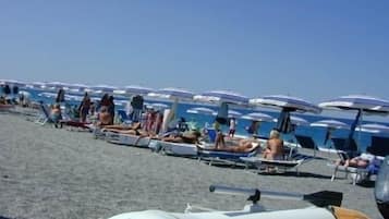 Une plage bordée de rangées de transats et de parasols, une tour de surveillance pour les sauveteurs et un panneau indiquant « EUROPA 24 ».