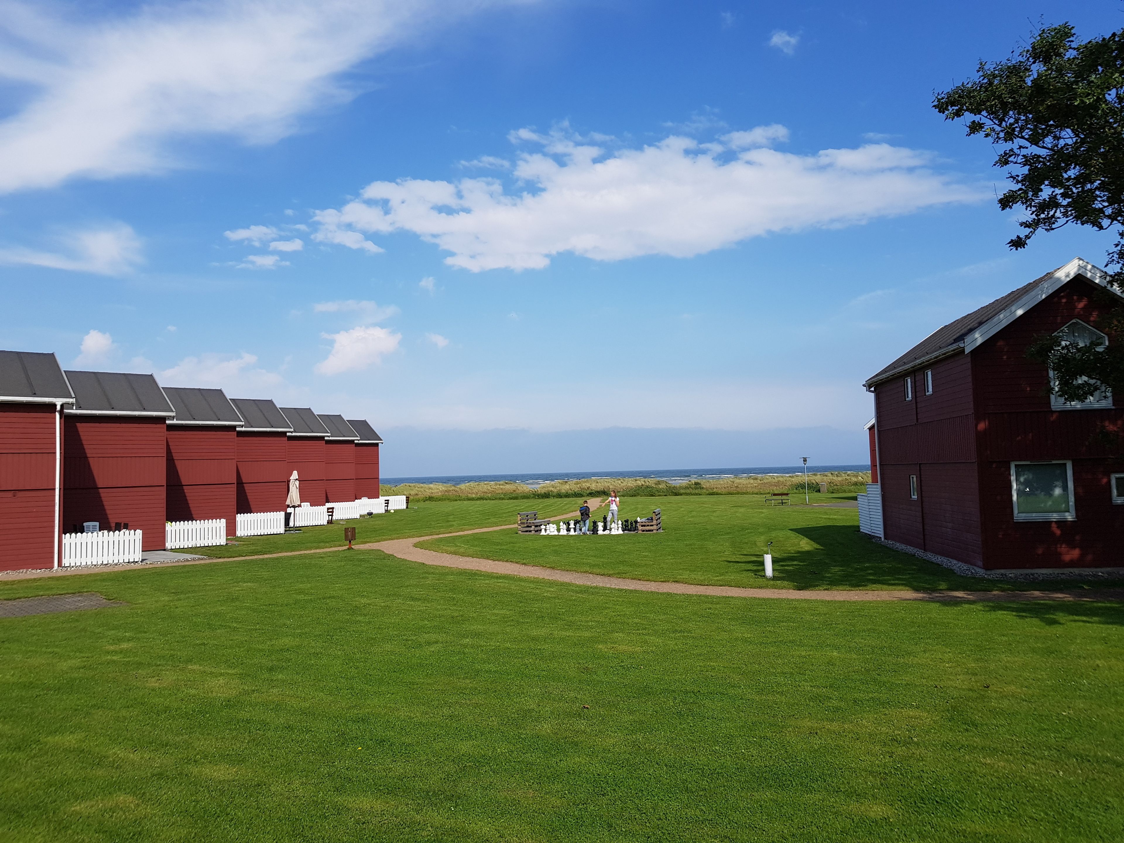 A red barn with a white picket fence, a grassy field, and a clear blue sky.