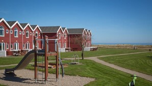 A playground with a slide and swings, a picnic table, and a walking path.