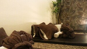 A room with a sofa, a small table, a potted plant, and a wall with a leaf pattern. - Hotel Livemax Chiba Mihama (Chiba)