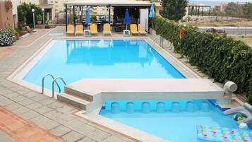 Una piscina al aire libre, sombrillas, sillones reclinables de piscina