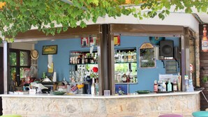 Un bar con mostrador de piedra, taburetes y una variedad de botellas y vasos.