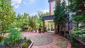 A courtyard with a brick pathway, potted plants, and a bench. - Hotel Morgenland (Berlin)