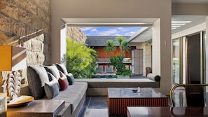 Un interior moderno con una pared de piedra, un área de descanso con cojines, una pequeña piscina y vistas al exterior.