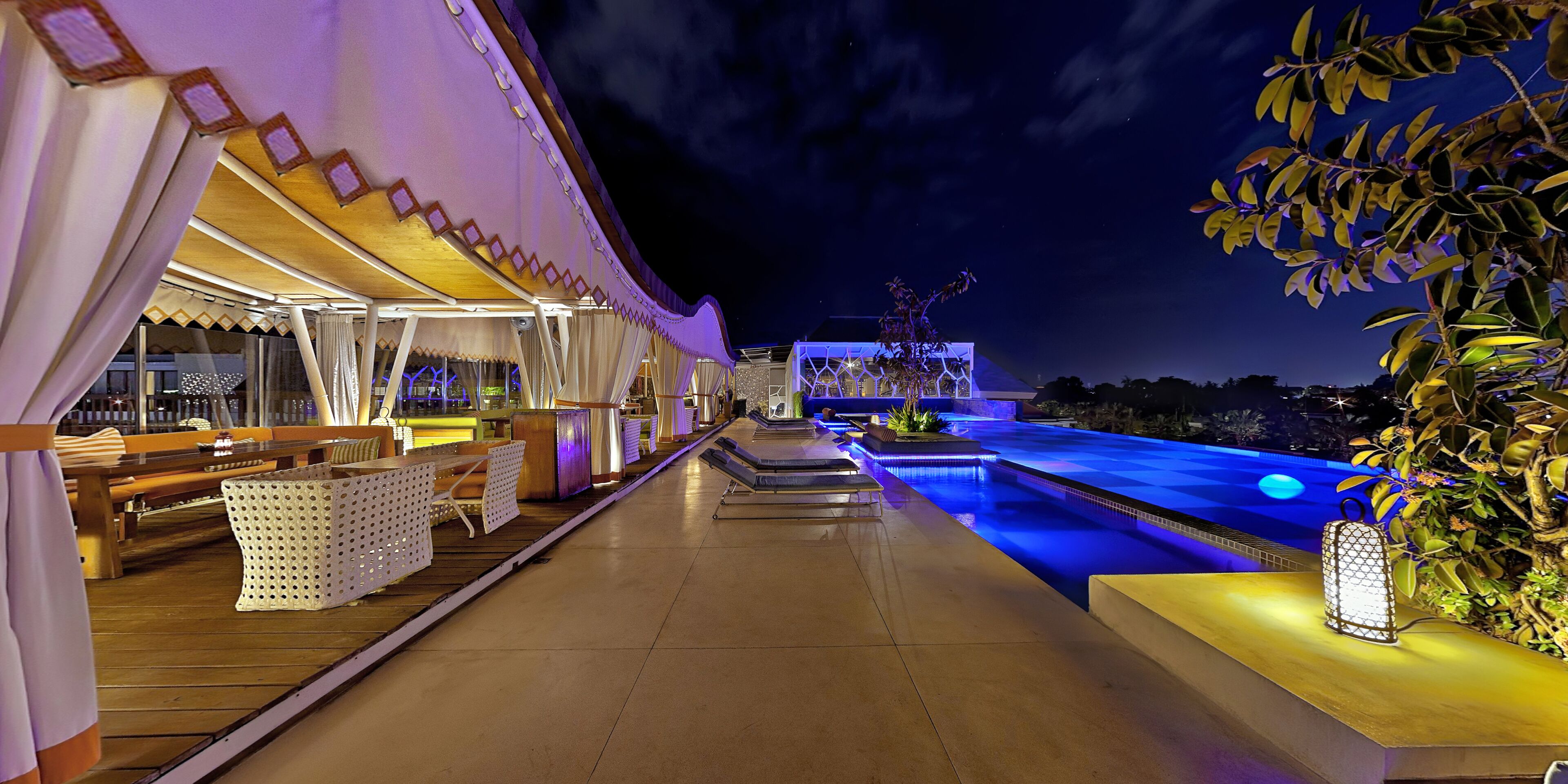 A poolside area with a seating area and a view of the pool.