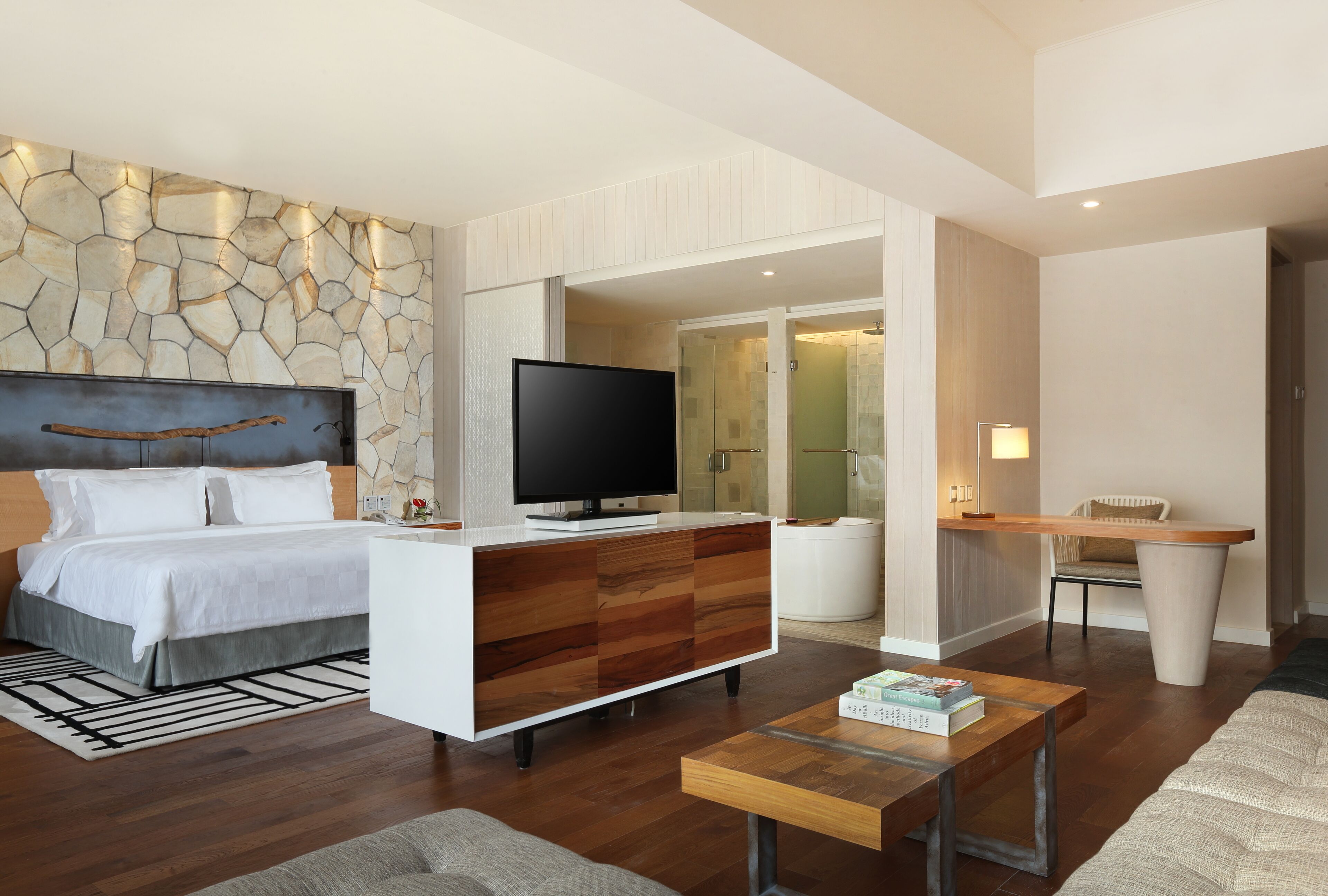 Ein modernes Hotelzimmer mit einem Bett, Fernseher, einem Holzschrank und einem kleinen Couchtisch.