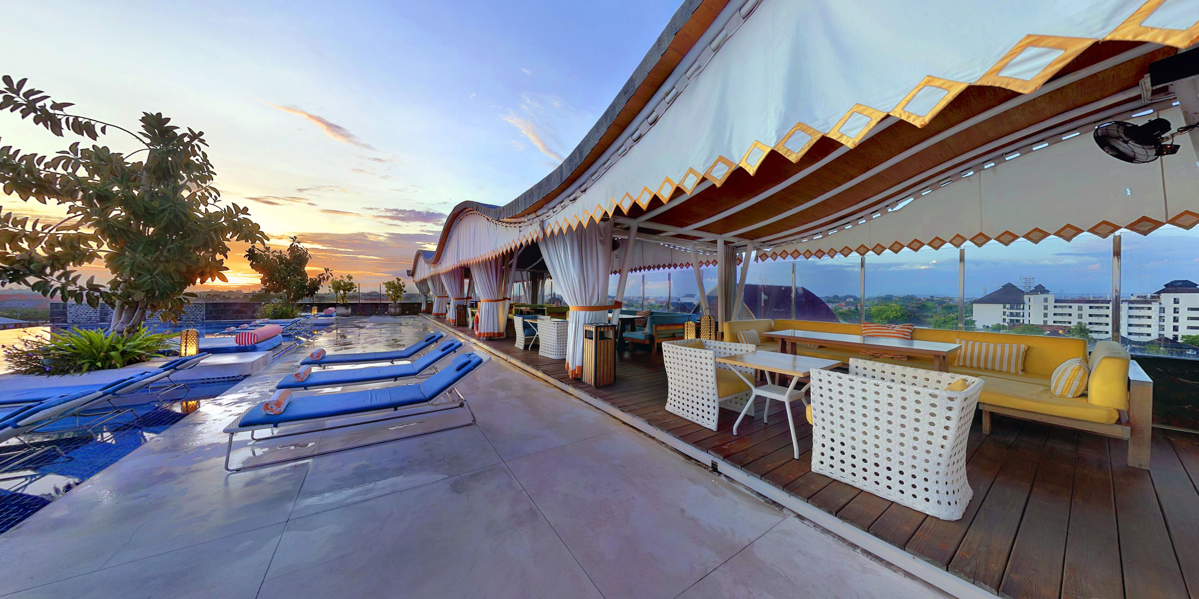 Uma área de lounge no terraço com espreguiçadeiras, espaço para sentar com almofadas e vista para a paisagem urbana.