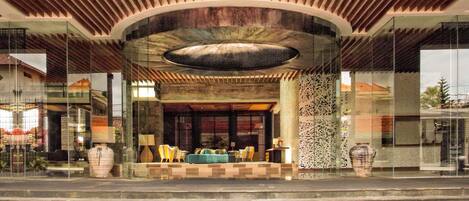 A modern lobby with a curved ceiling, seating area, and a large vase.