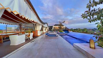 Zona de piscina con sillas de descanso, un espacio de estar cubierto y vistas a la piscina.