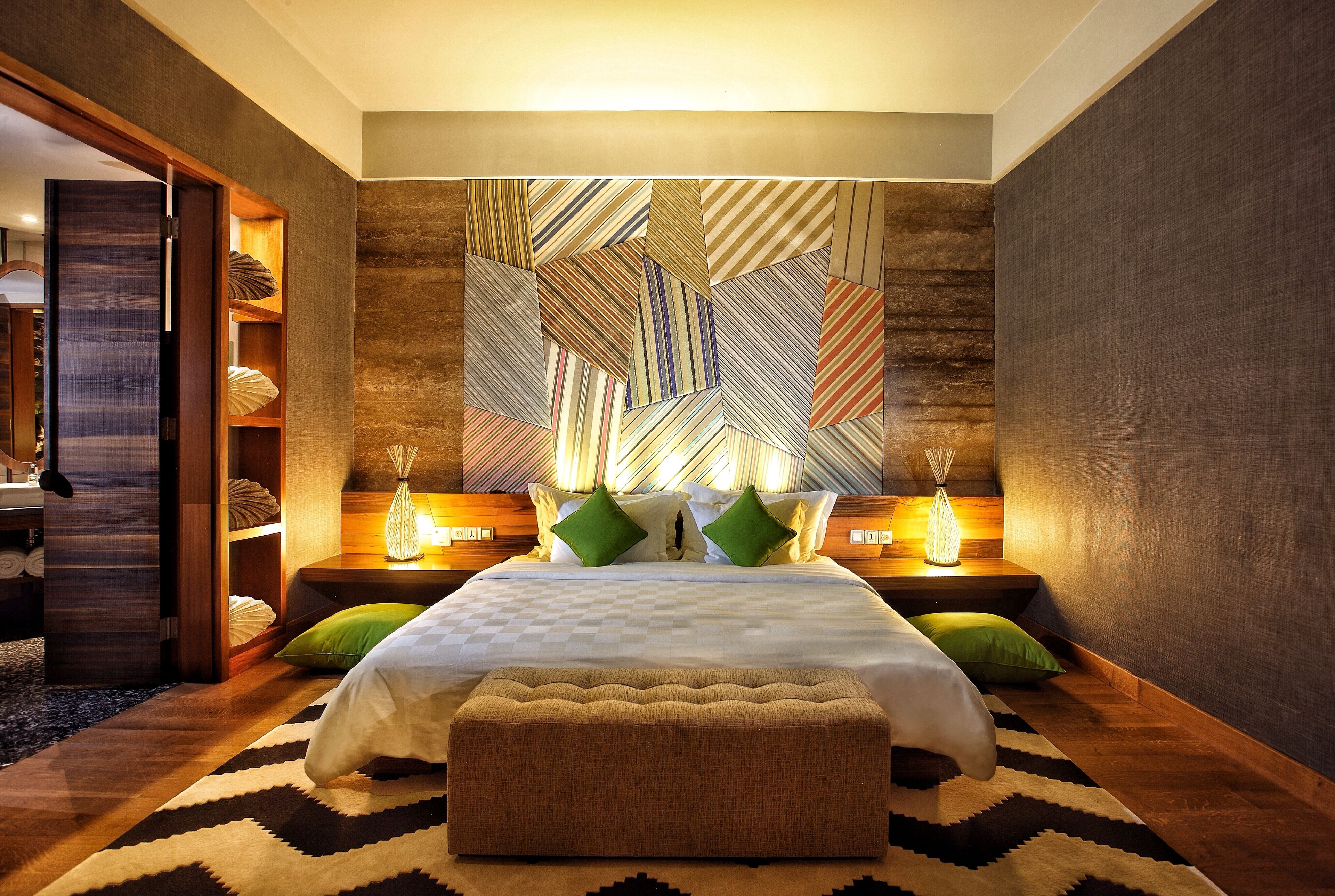 A modern bedroom with a large bed, a bench, and a geometric-patterned wall.