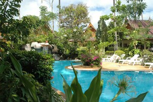 Una piscina al aire libre, sombrillas, sillones reclinables de piscina