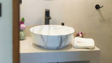 A bathroom with a round mirror, a white sink, and two pendant lights.