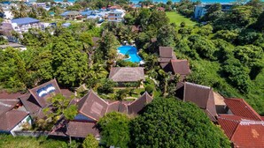 An aerial view of a resort with a swimming pool surrounded by lush greenery and traditional architecture. - Palm Garden Resort (Rawai)
