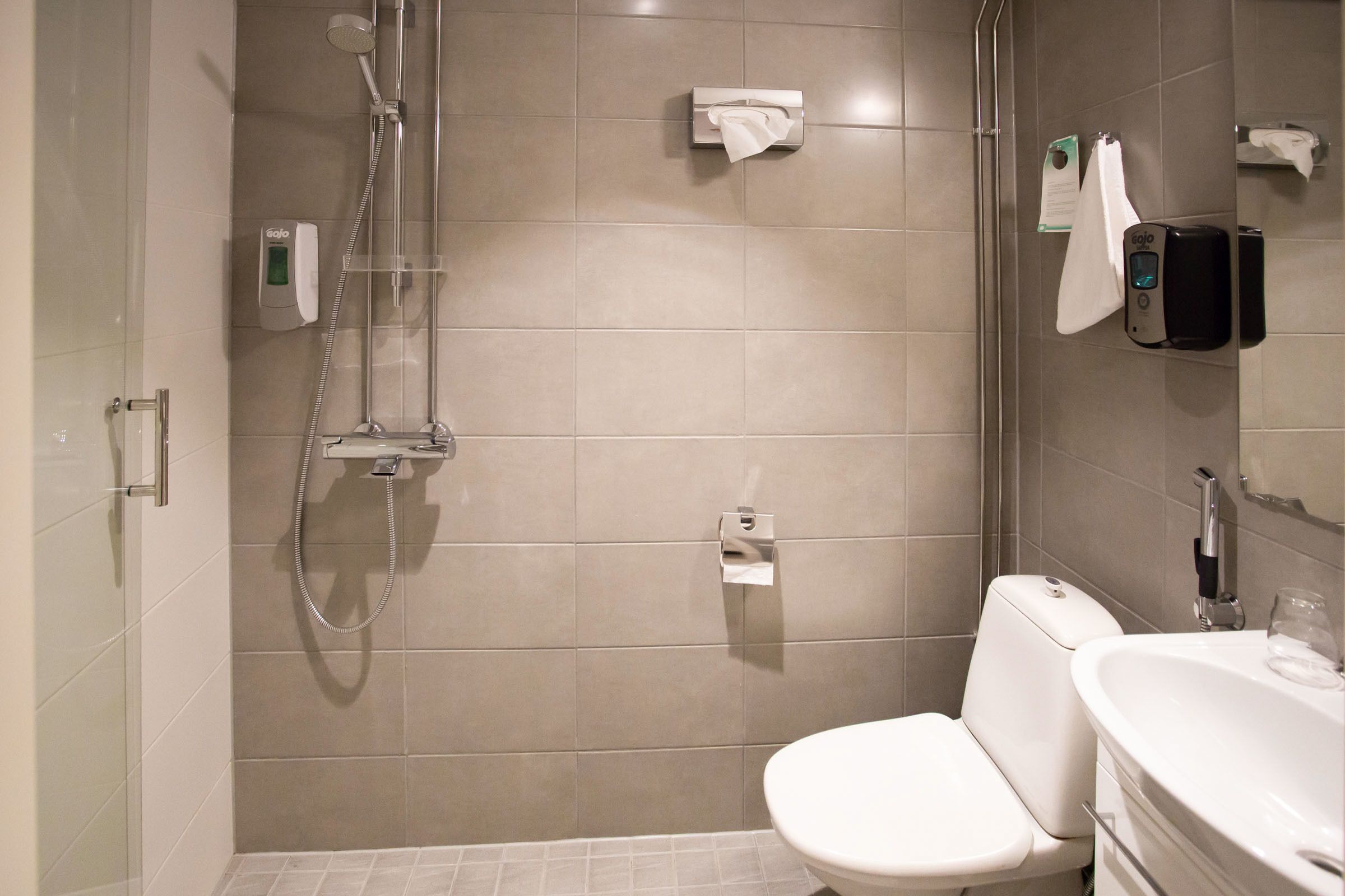 Uma casa de banho moderna com chuveiro, sanita e lavatório.