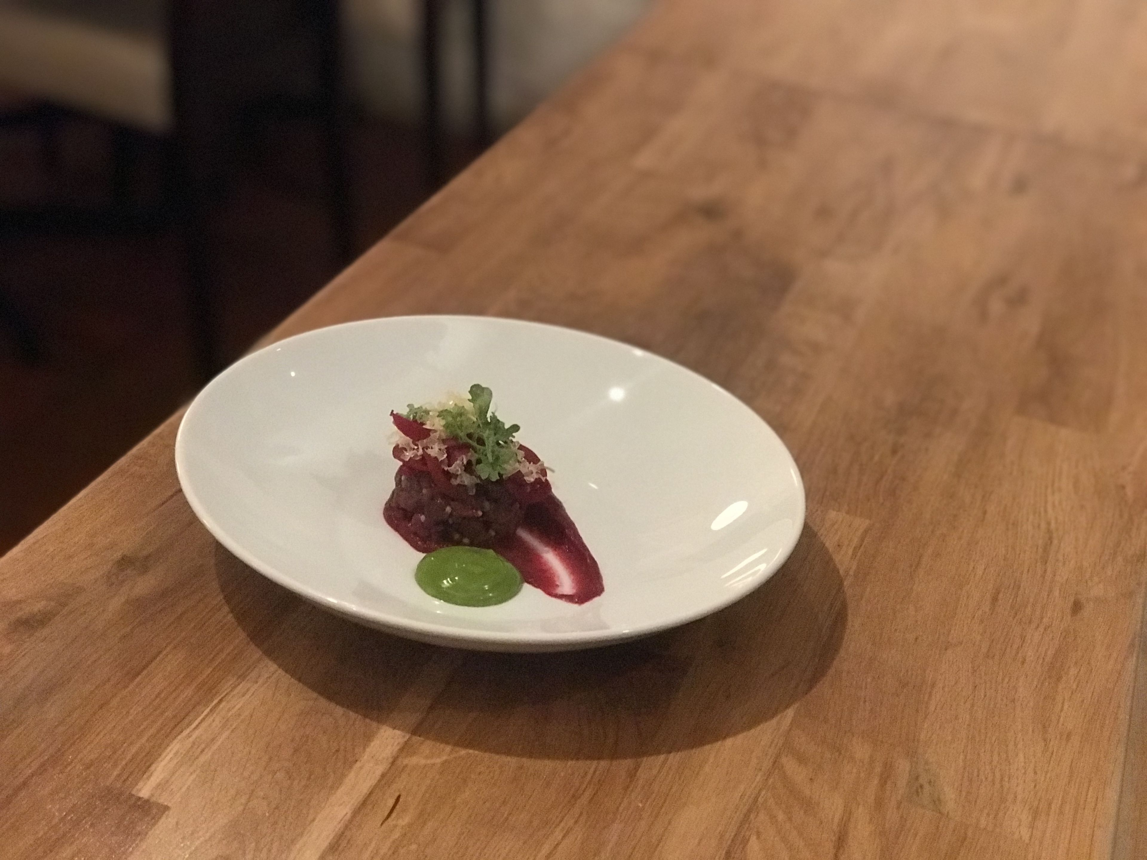 A white plate with a small portion of food on a wooden table.
