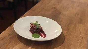 A white plate with a small portion of food on a wooden table.