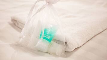 A white towel and a clear plastic bag with a product label on a bed.