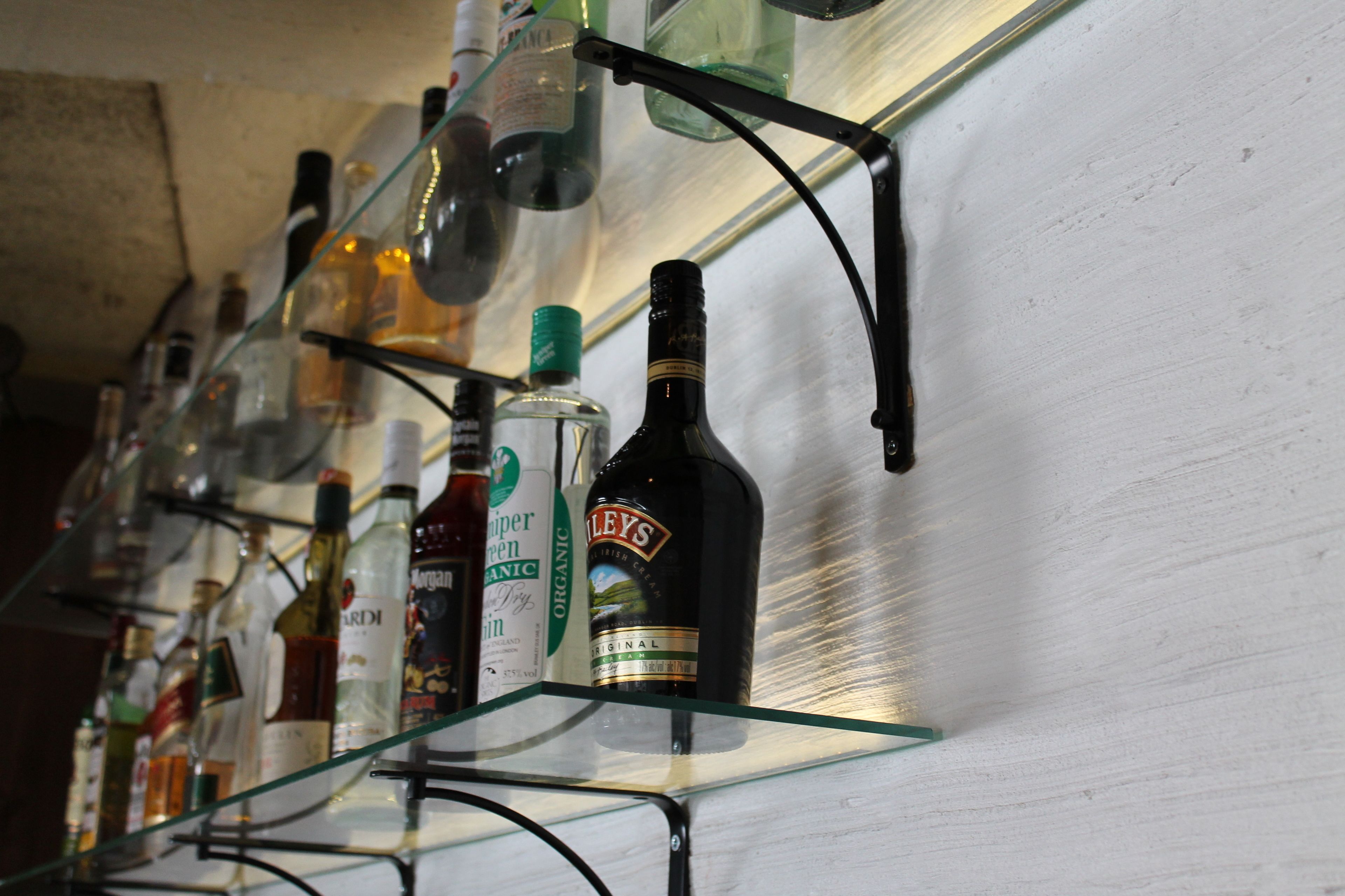 Een bar met planken vol verschillende drankflessen.
